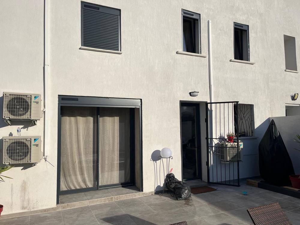 Façade blanche avec un volet roulant gris anthracite et une baie coulissante